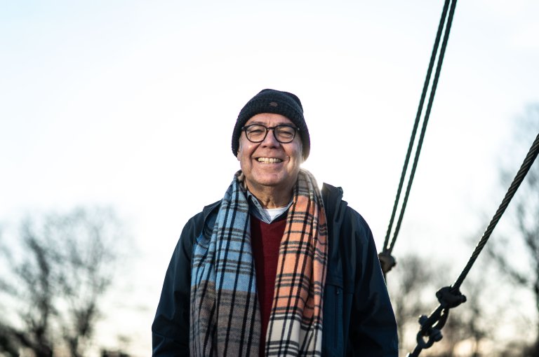 Halvportrett mann med lue og fargerikt skjerf, ute.