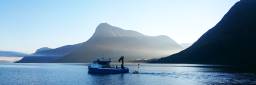 Båt på Sulafjorden trekker på en bøye som skal måle vind. Fjorden er omkranset av fjell, klar, blå himmel.
