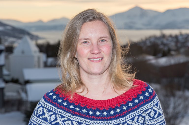 Signe Aaboe står med rød, hvit og blå mariusgenser og bak henne skimtes Tromsø by.