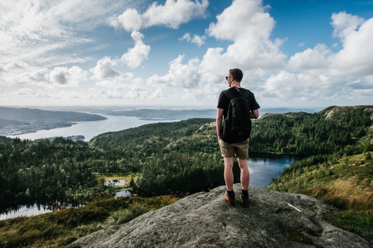 Mannlig fjellvandrer som ser på utsikt over fjell og sjø