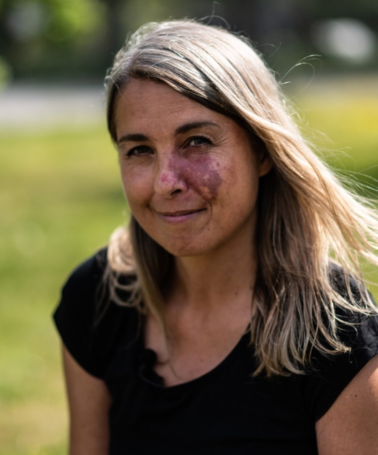 Portrettfoto av Reidun Gangstø med blondt hår og grønn natur i bakgrunn.