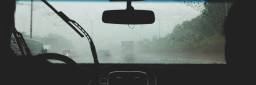 To personer i en bil som kjører i byen i regnvær