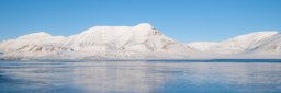 Snøkledde fjell og knallblå himmel på Svalbard